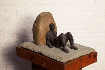 Boaz Vaadia Oded 2nd (#143) (2016), a bronze and bluestone figurative sculpture featuring a reclining human figure resting against a boulder, measuring 11 x 21 x 15 inches. This stacked stone artwork merges ancient techniques with modern abstraction, avai